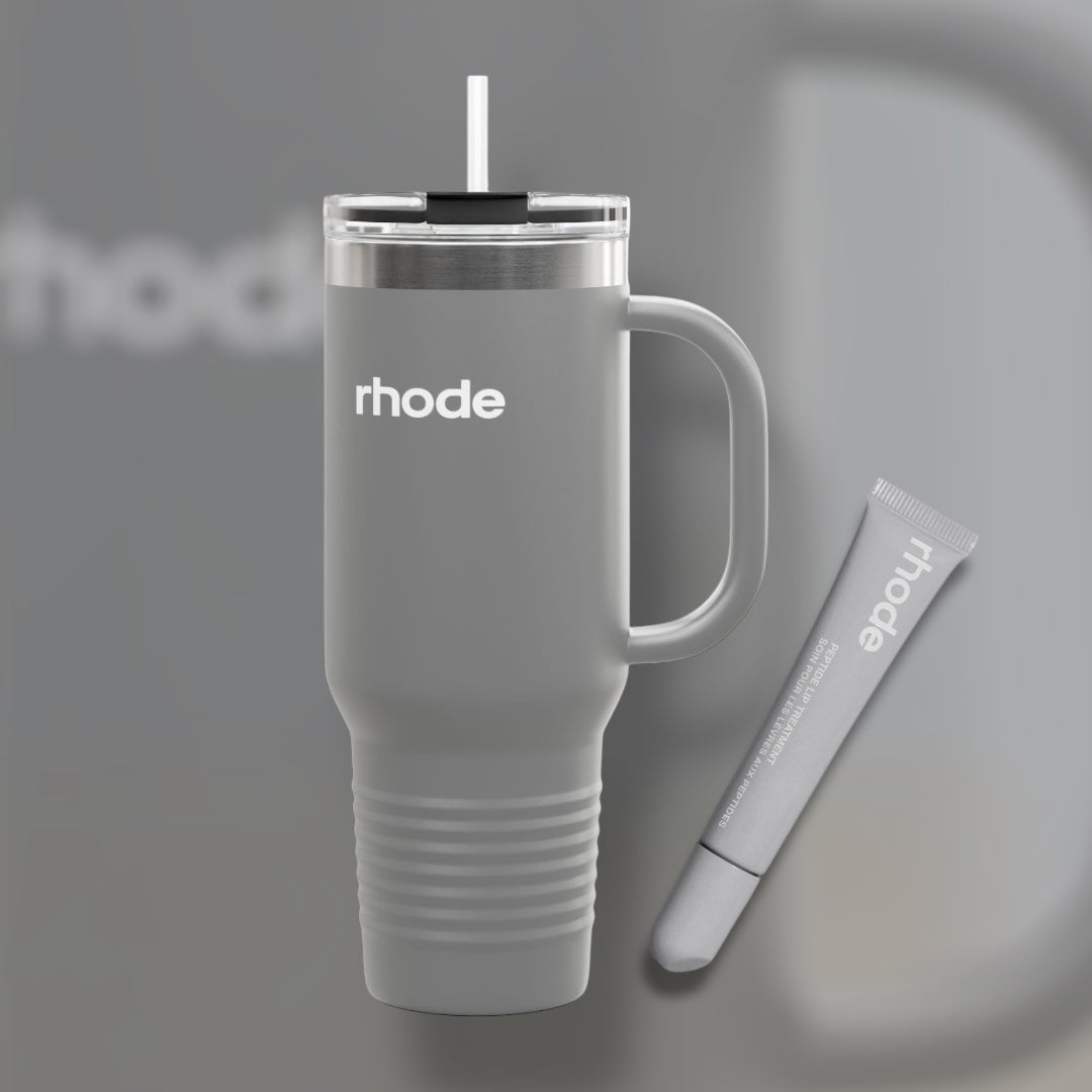 Gray travel mug with handle and straw, featuring the brand 'rhode', on a gray background.