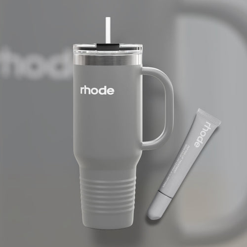 Gray travel mug with handle and straw, featuring the brand 'rhode', on a gray background.